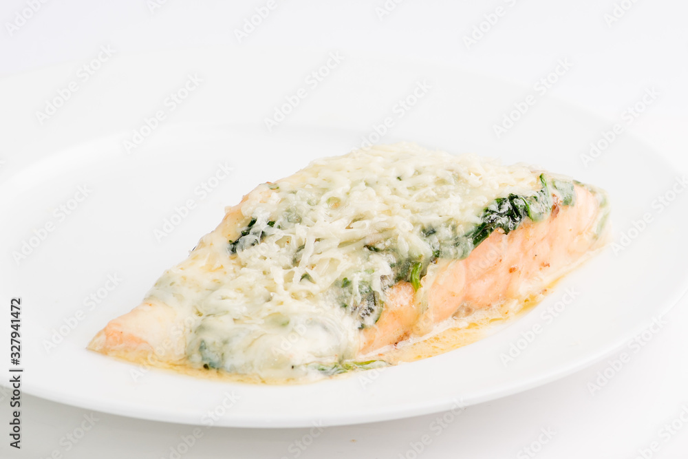 piece of salmon in a creamy sauce with spinach on a white plate piece of salmon in a creamy sauce with spinach on a white plate