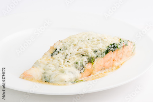 piece of salmon in a creamy sauce with spinach on a white plate