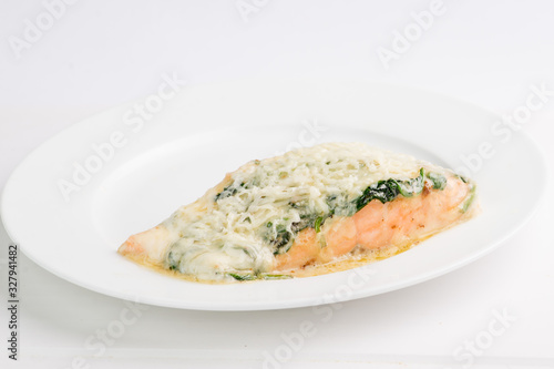 piece of salmon in a creamy sauce with spinach on a white plate