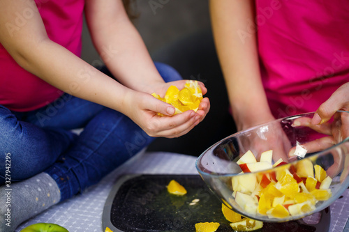 daughter and mom cut a fruit salad consisting of apple orange and mandarin