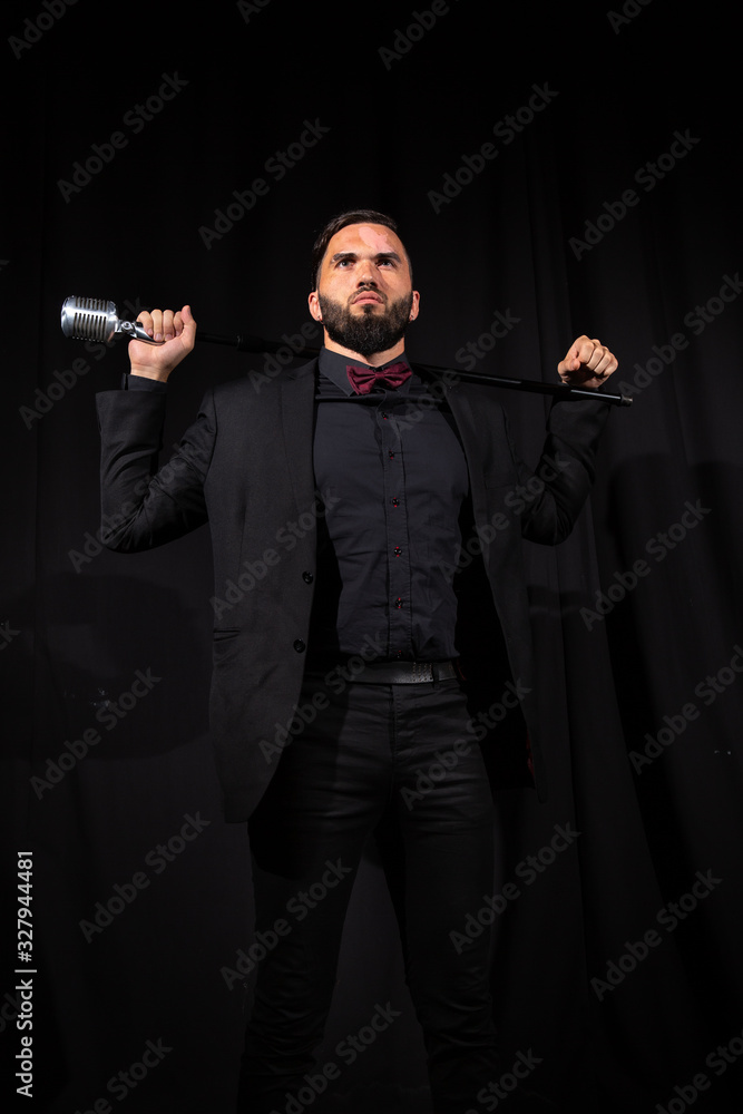 Serious male singer with microphone on black Serious male singer with microphone on black