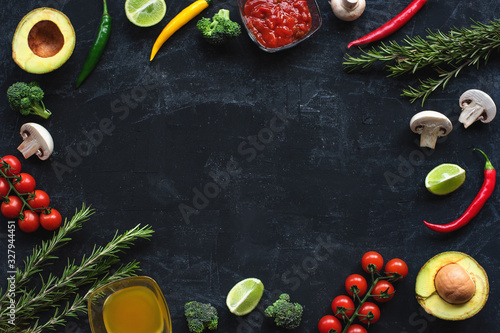 Ingredients for Italian cuisine: tomatoes, mushrooms, broccoli, chilli peppers, avocado, rosemary, olive oil and red sauce on a black background. Top view, flat lay, copy space.