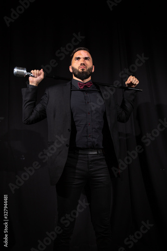 Serious male singer with microphone on black photo