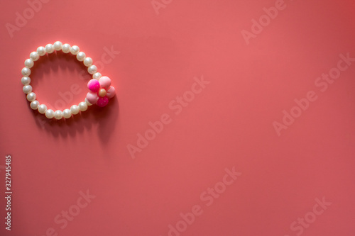 Elegant pearl female jewelry with flower on the pink background. Copy space.