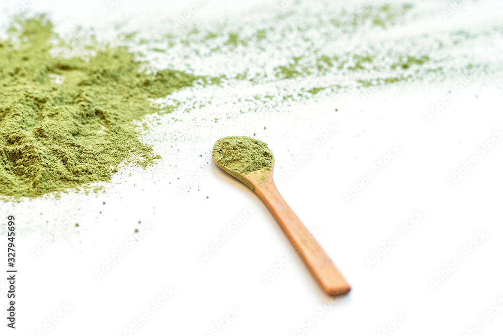 Powdered green matcha tea and wooden spoon isolated on white background