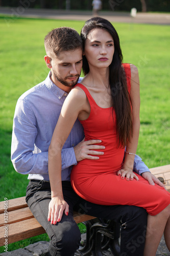 Beautiful couple of man and woman sitting on a bench in a park. Romantic theme with a girl and a guy. Spring Summer theme  relationship, love, Valentine's day © subjob
