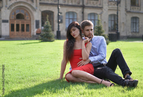 Beautiful couple of man and woman sitting and lying on the grass. Romantic theme with a girl and a guy. Spring Summer picture relationship, love, Valentine's day