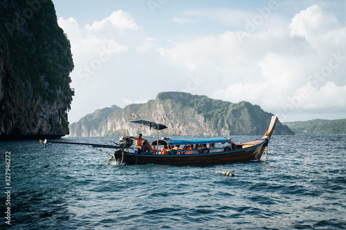 Longtail boat in middle of the sea with islands on the background and tourists inside