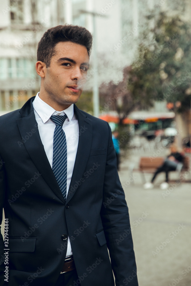 Boy in suit smoking with vaper