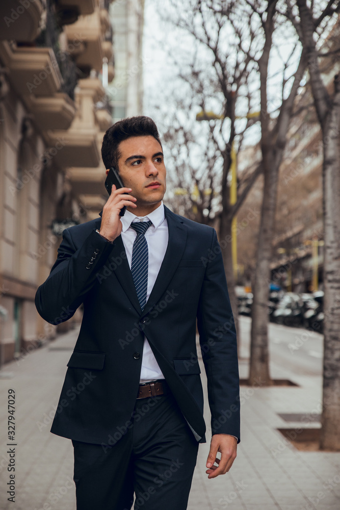 Close up of young boy walking with blue suit and calling by phone in city