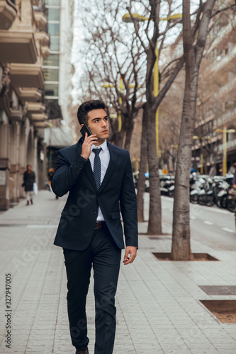 young boy walking with blue suit and calling by phone in city