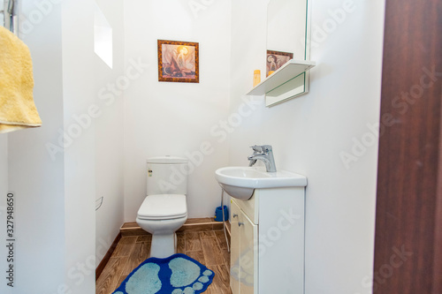 Bathroom in the guest house in a white tile with a toilet and sink