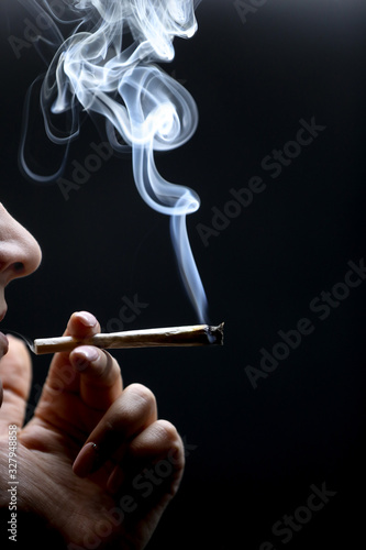 Wallpaper Mural Woman hand holding cigarette. Smoking cannabis joint. Medical use. Black background. Torontodigital.ca
