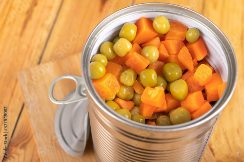 An open can with a mix of peas and carrots. Food preserved in the household.