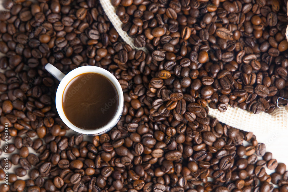 Coffee beans in a rustic coffee bag, full cups and hand holding the coffee Coffee beans in a rustic coffee bag, full cups and hand holding the coffee