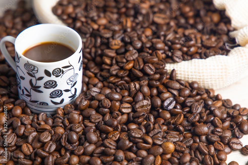 Coffee beans in a rustic coffee bag, full cups and hand holding the coffee Coffee beans in a rustic coffee bag, full cups and hand holding the coffee
