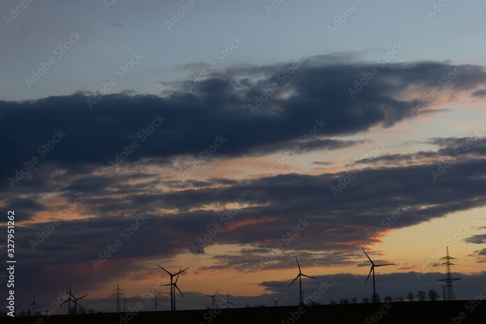 Windräder und Strommasten auf einem Feld bei Sonnenuntergang 