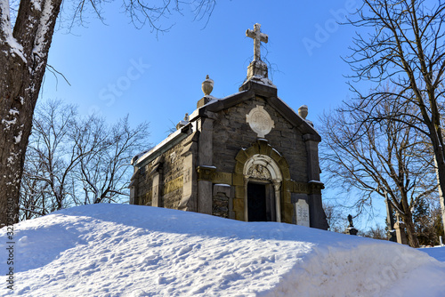 Old mausoleum with snow covered ground on sunny day blue sky, Mount Royal Cemetery photo