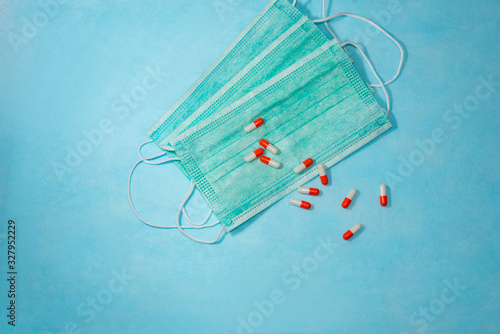 The concept of protection against airborne diseases. Pills or capsules on a disposable surgical mask over blue background.