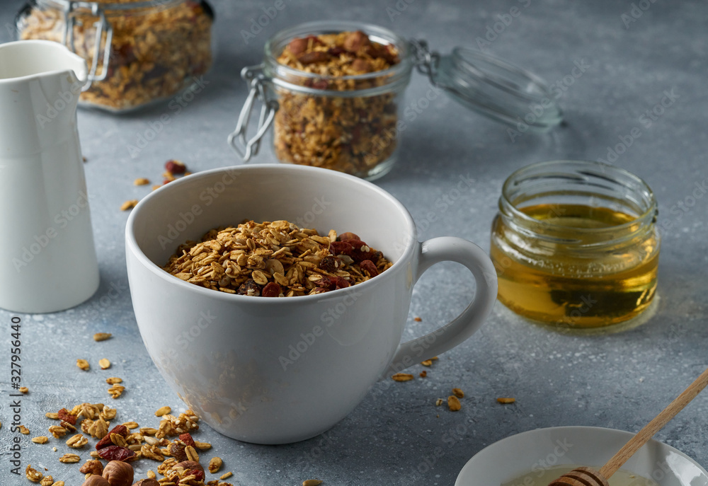 Fototapeta premium Homemade granola from mix of oat cereals with dry fruits, nuts and seeds on a grey concrete table concept of healthy breakfast. Slow living