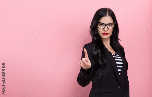 Young woman pointing at something on a pink background