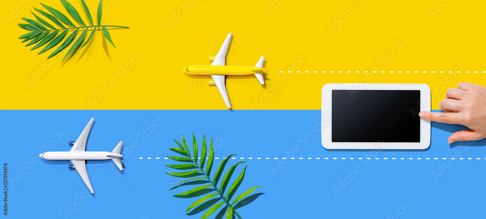 Person using a tablet computer with small airplanes from above Person using a tablet computer with small airplanes from above