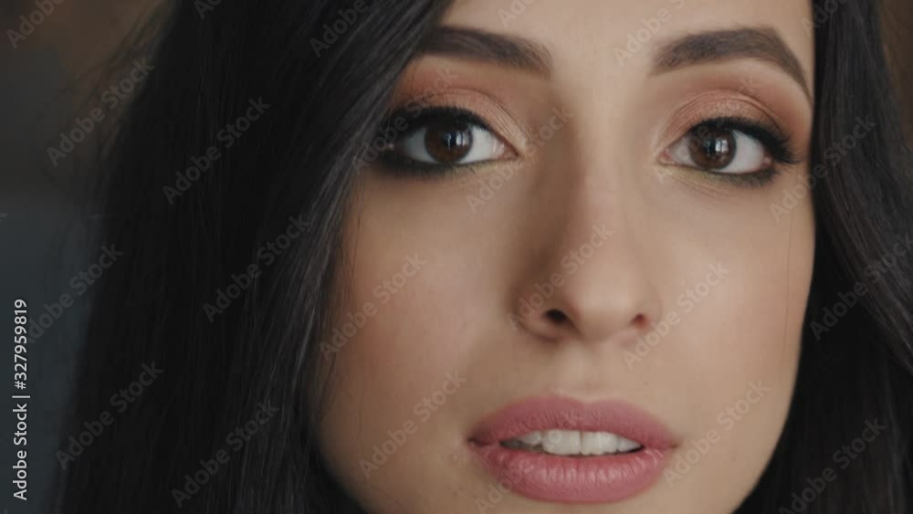 Big close up shot of adorable young brunette woman face with gorgeous hair lovely brown eyes trendy makeup indoors in loft cafe Big close up shot of adorable young brunette woman face with gorgeous hair lovely brown eyes trendy makeup indoors in loft cafe