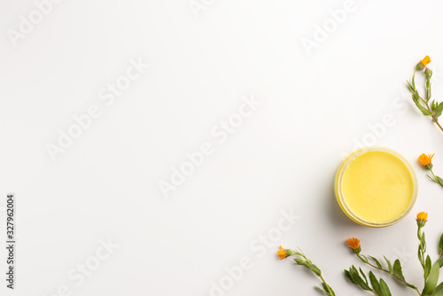 Organic cosmetic concept. Flowers of calendula and jar of skin care cream, isolated on white background. Flat lay, top view, copy space.