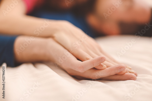 Hands of young couple sleeping in bed