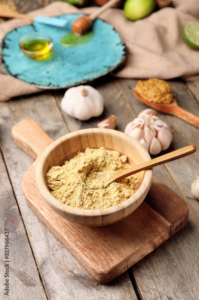 Bowl with dry mustard on wooden background