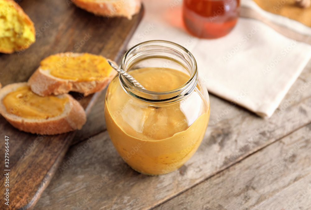 Jar of tasty honey mustard sauce on wooden table Jar of tasty honey mustard sauce on wooden table