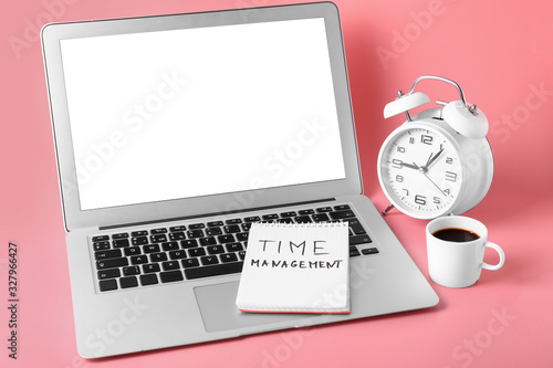 Laptop, notebook, coffee and alarm clock on color background. Time management concept