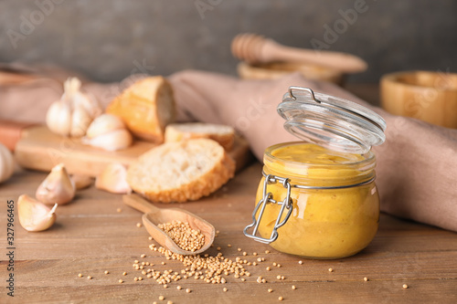 Jar of tasty honey mustard sauce on wooden table
