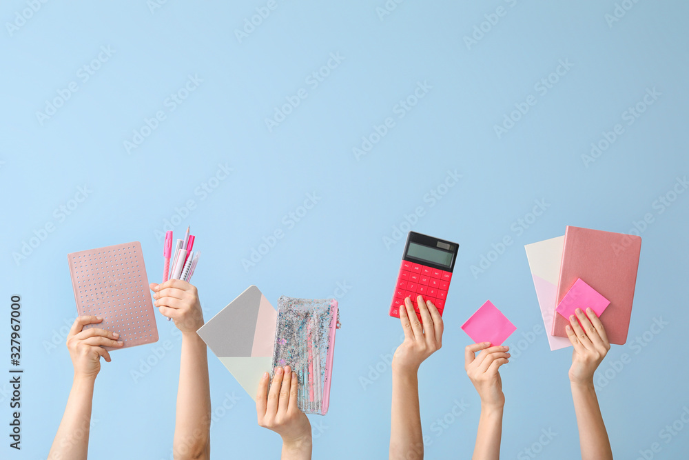 Many hands with school supplies on color background Many hands with school supplies on color background