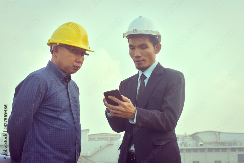 Contractor two people talking discussion looking at mobile smart phone to check inspection exclusive cooperation building construction Contractor two people talking discussion looking at mobile smart phone to check inspection exclusive cooperation building construction