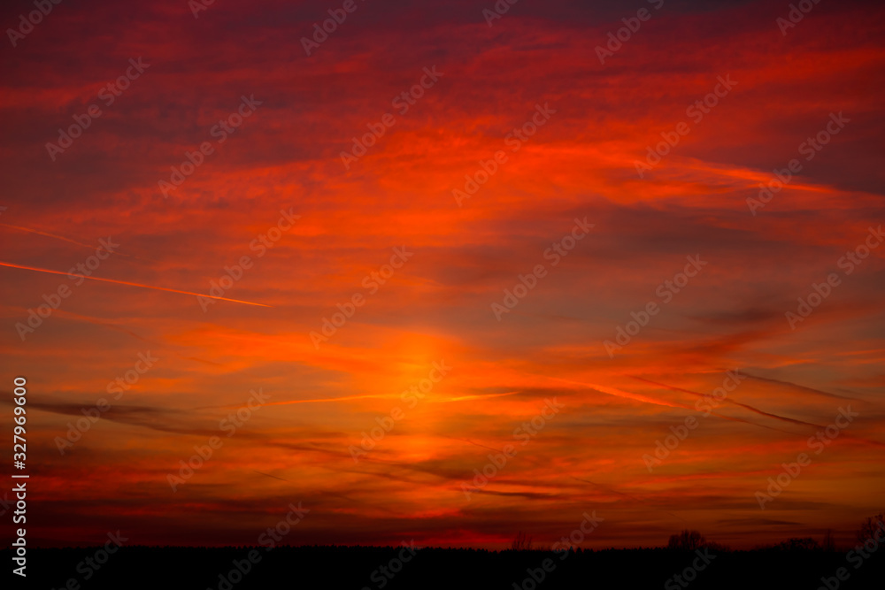 Fiery red sunset with the effect of a solar pillar in the sky