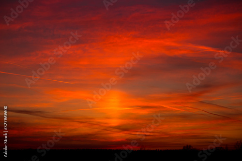 Fiery red sunset with the effect of a solar pillar in the sky