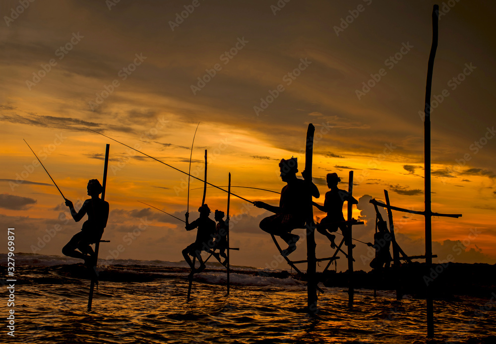 Silhouettes of the traditional Sri Lankan stilt fishermen at the sunset in Koggala, Sri Lanka. Stilt fishing is a method of fishing unique to the island country of Sri Lanka