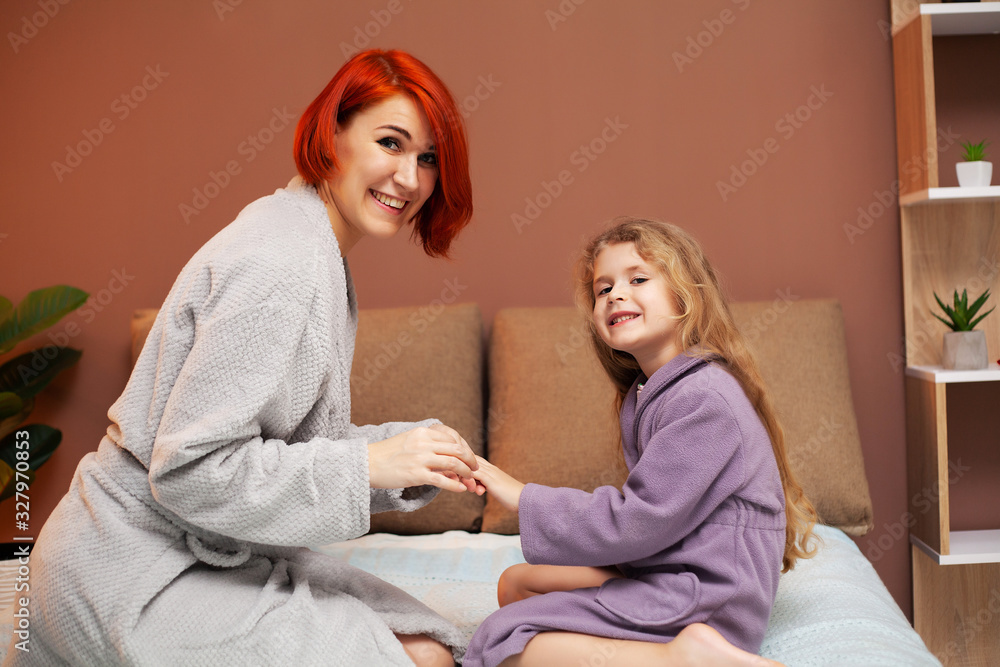 Obraz premium Mom makes daughter on the bed at home manicure