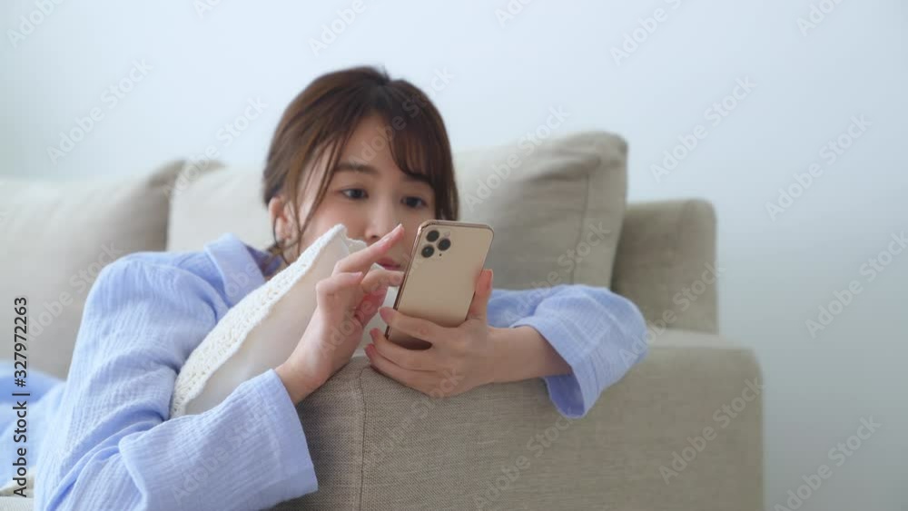 寝ながらスマホを使う女性 寝ながらスマホを使う女性