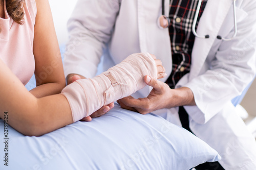 Bone specialist doctor examining serious injured woman at her arm with splint and bandage. Physician doctor talking to broken arm woman patient in the hospital. Healing in injured person concept.