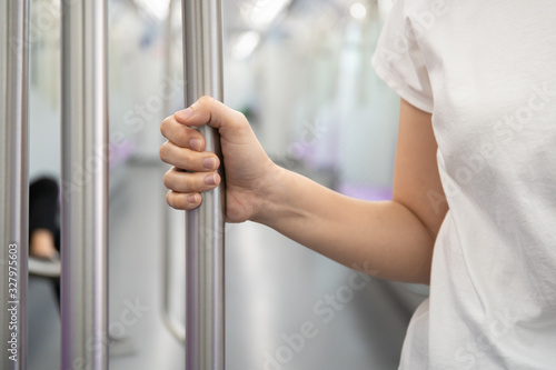 Woman tourist travel in the city by public city sky train system. Woman holding the hand rail in the train close up with copy space. Solo female tourist in modern lifestyle concept. Urban lifestyle.