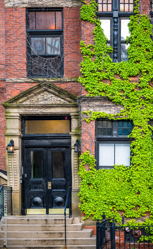 Red brick multi-story residential building with ivy wall on a street in old Boston