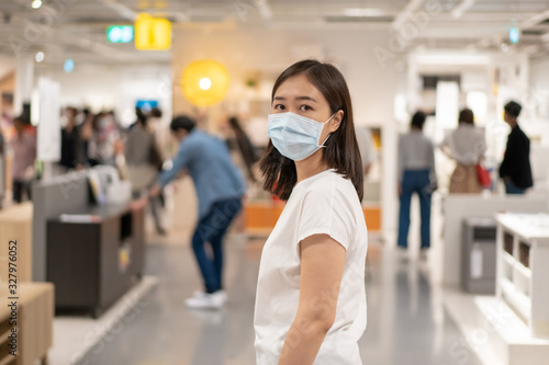 Asian young woman wearing a hygiene protective mask over her face while walking at the crowded shopping mall. Healthcare and sickness prevention from coronavirus, Covid19 influenza in crowded place.