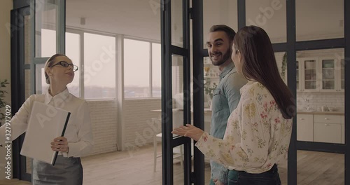 Happy Couple with real-estate agent visiting house for sale or for rent, Young man and woman cheerful at home. Loving people buying an apartment. Immovables market 4K slow motion video. 
