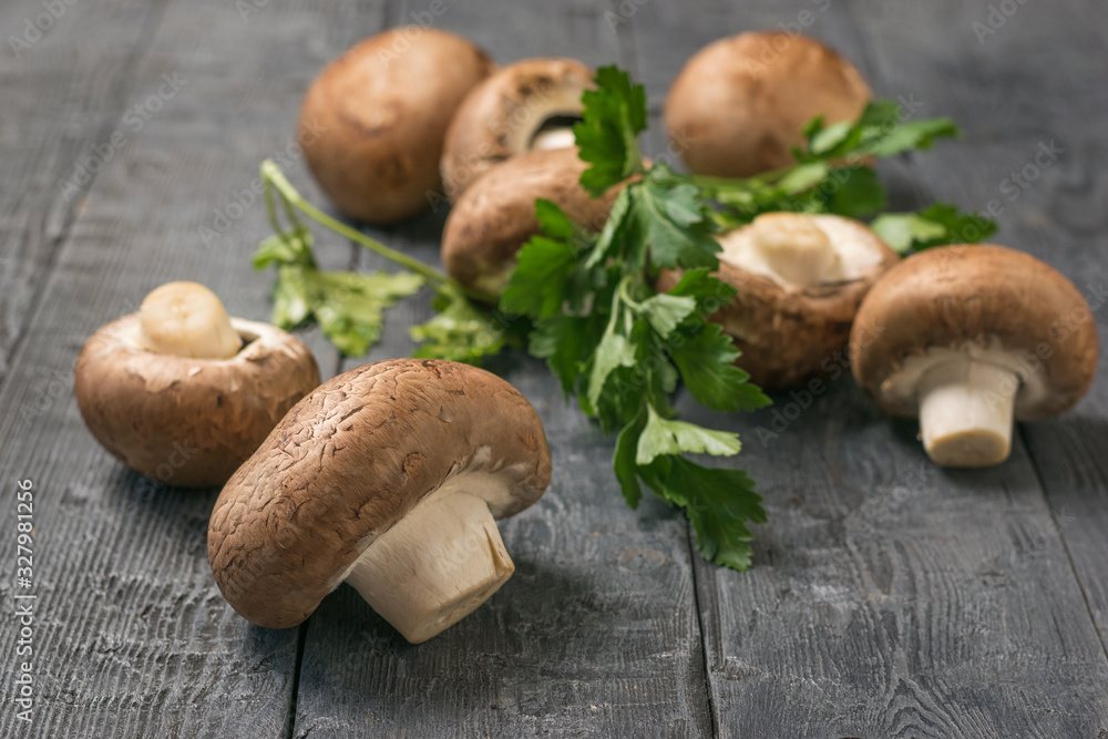 Royal mushrooms are scattered on a black wooden table with parsley leaves. Vegetarian food. Royal mushrooms are scattered on a black wooden table with parsley leaves. Vegetarian food.