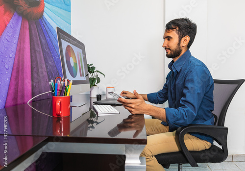 Side view. Young bearded businessman sitting in office
