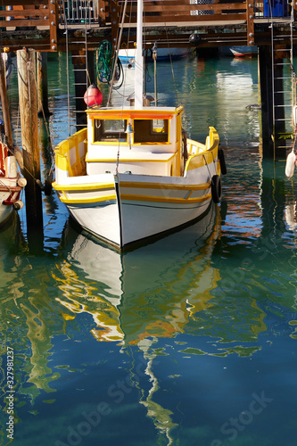 Old wood fishing boat fastened to a dock in calm waters on a sunny day © Jill Greer