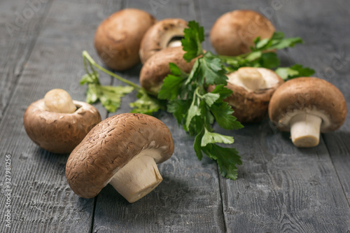Royal mushrooms are scattered on a black wooden table with parsley leaves. Vegetarian food.
