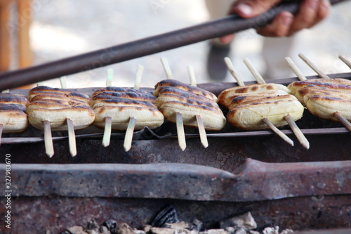 Rows peeled off banana  fruitson bamboo skewer roasting on charcoal stove in Thailand. photo